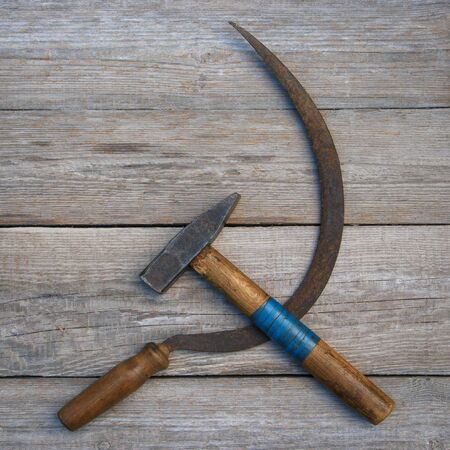 The sickle and the hammer lying on a wooden boardの写真素材