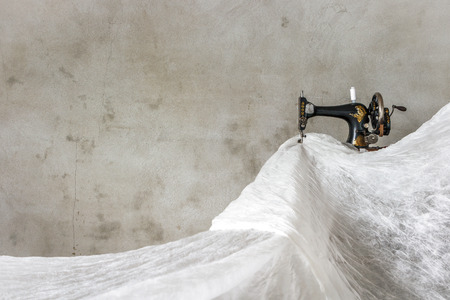 The old sewing machine and a lot of white fabricの写真素材