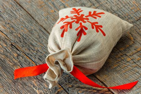 Small bag with a red ribbon on a wooden boardの写真素材