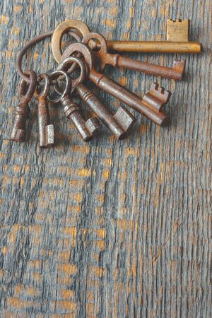 A bunch of old keys on a wooden boardの写真素材