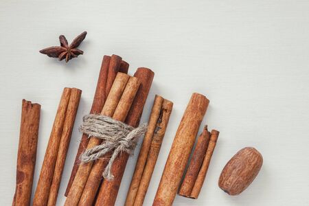 Cinnamon sticks and nutmeg on a white painted boardの写真素材