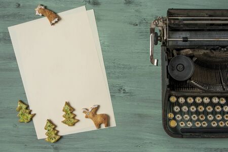 Figure Christmas cookies rests on a blank sheet of paper next to the typewriterの写真素材