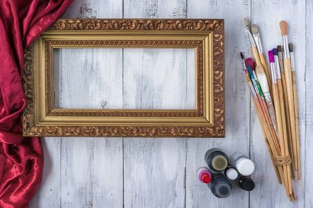 Old Framing frame lies on a white board next to the bottles of paint and brushesの写真素材