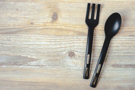 Spoon and fork in black lie on a wooden boardの写真素材