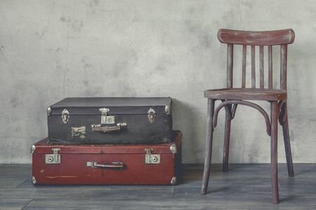Old suitcase and a wooden chair standing in an empty roomの写真素材