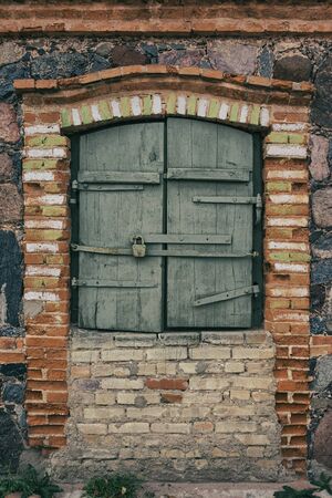 Old stone house with wooden shutters on the windowの写真素材
