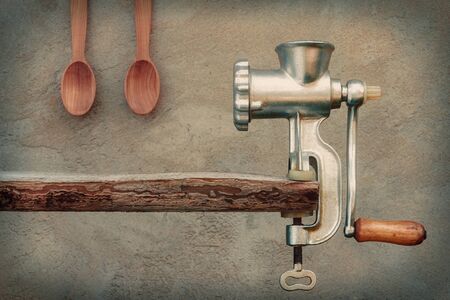 Old grinder and a wooden spoon on a background of a concrete wallの写真素材