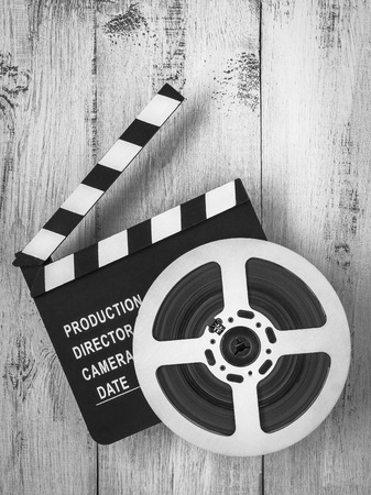 Clapperboards and the reel of film lie on a wooden board.Black and white photoの写真素材