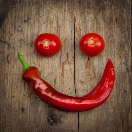 Bulgarian pepper and two tomatoes lying on an old wooden boardの写真素材