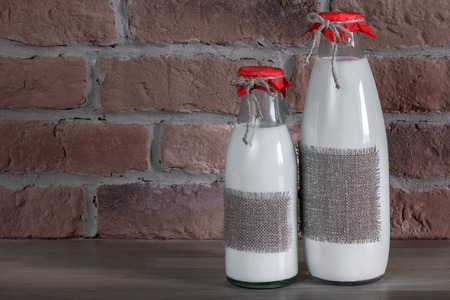 Two bottles of milk standing on a wooden tableの写真素材