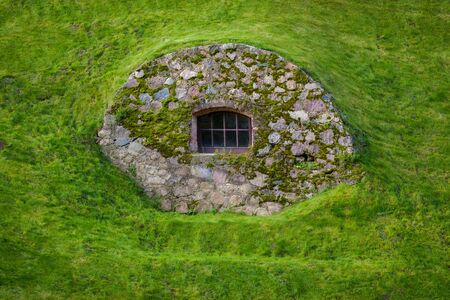 Window in a stone wall on a green hillsideの写真素材