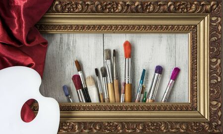 Brushes, a palette, a picture frame and a red silk cloth in the artist's studioの写真素材