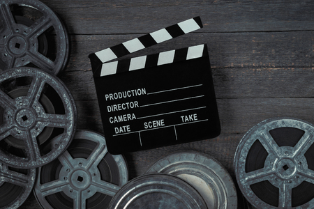 Clapperboards  and reel of film lie on the old boardの写真素材