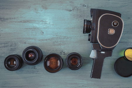 Old movie camera with interchangeable lenses and color filters lie on the painted deskの写真素材