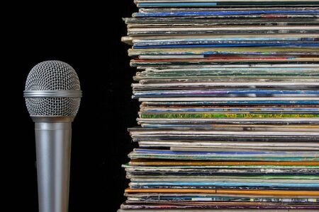 Pile of old vinyl records and microphone on a black backgroundの写真素材