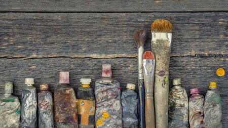 Artist brushes and old tubes of oil paint lying on the table in the Studioの写真素材