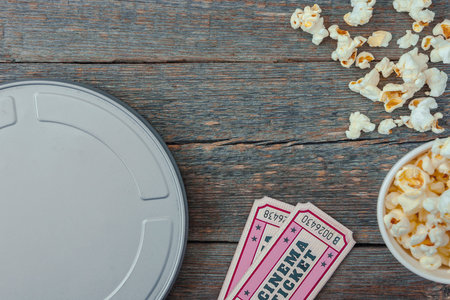 Tin box with movie tickets to the cinema and pack with popcorn stand on a wooden table.