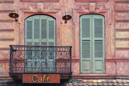 Fragment of the old city cafe with a sign on the balcony and windows with shuttersの写真素材