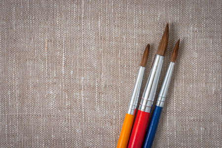 Brushes of the artist with colored handles lie on canvas. Artistic equipmentの写真素材