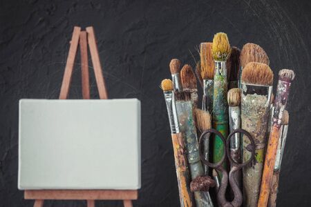 Artistic equipment. The artist's brush and stretcher with a clean canvas on the background of a gray concrete wall in the workshop. Stylized photo.の写真素材