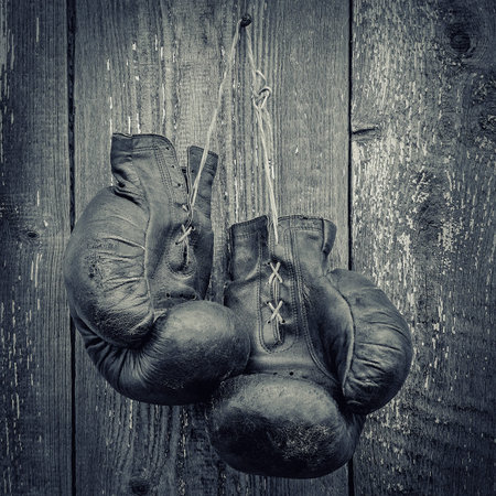 Old boxing gloves hanging on a wooden wall.Black and white photo