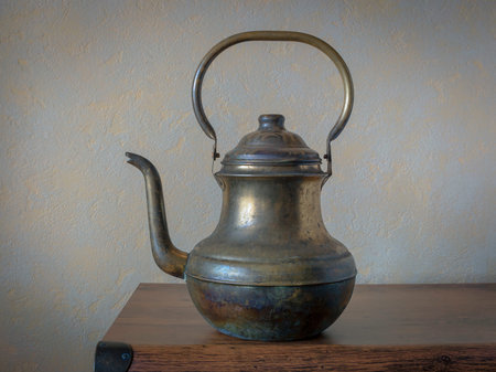 An old brass kettle with a handle stands on the kitchen shelfの写真素材