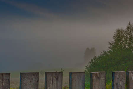 Misty early morning with a wooden fence in the villageの写真素材