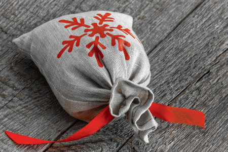 Canvas bag with a painted snowflake and a Christmas gift and tied with a red ribbon.Close upの写真素材
