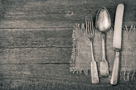 Fork, spoon and knife on an old wooden board.Tnted photoの写真素材