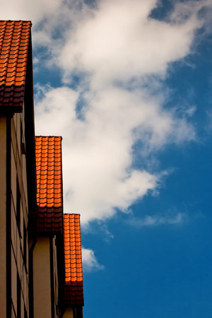 Fragments of tiled roofs of half-timbered houses filmed against a blue sky