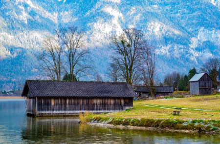 Beautiful lake in the mountains, lonely bench, in the background a wooden house, behind the houses...