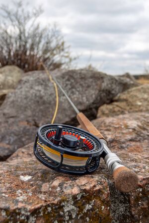 A fly fishing rod lies on large stonesの写真素材