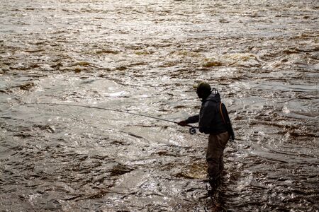 silhouette of a fisherman at sunset in a stormy riverの写真素材