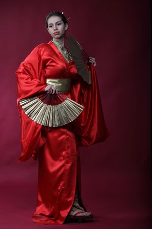 Beautiful brunette girl in a japanese kimono with two funsの写真素材