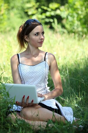 Girl with a notebook sit on the gladeの写真素材