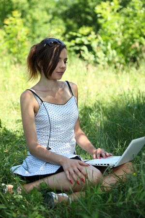 Girl with a notebook sit on the gladeの写真素材