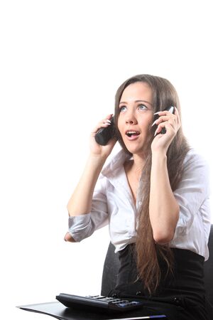 Surprised businesswoman with a file and calculator speak by two phonesの写真素材