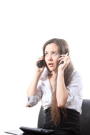 Surprised businesswoman with a file and calculator speak by two phonesの写真素材