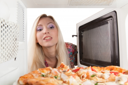 Girl preparing pizza in the microwaveの写真素材