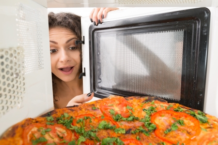 Attractive girl open  a microwaveの写真素材