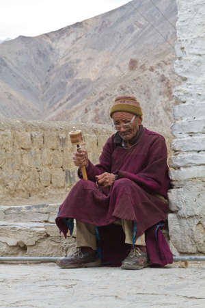 Indian old man with the prayer wheel on the threshold of the templeのeditorial素材