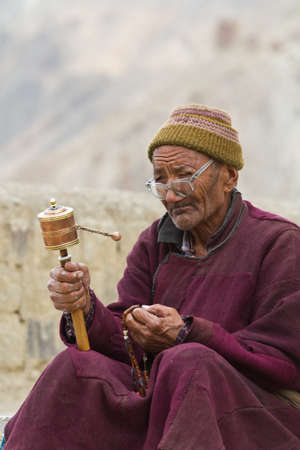 Indian old man with the prayer wheel on the threshold of the templeのeditorial素材