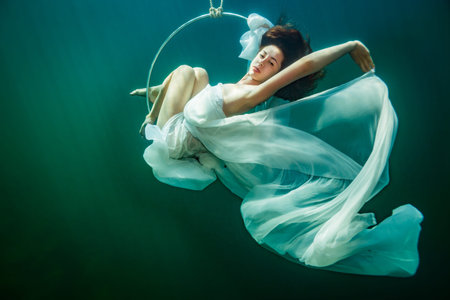Young graceful woman in a dress on the gymnastic hoopの写真素材