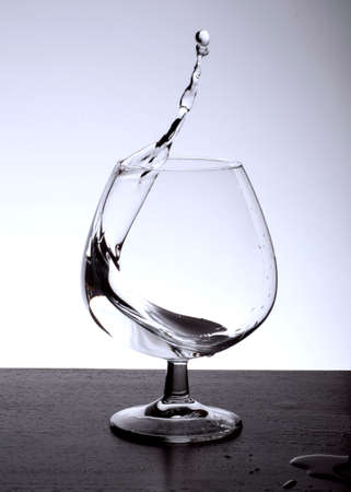 Water rises beautifully from the glass and splashes out in a splash.の写真素材