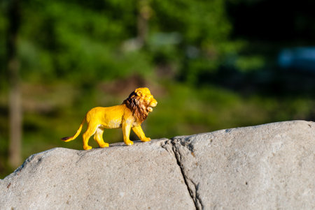 Plastic figurine of a toy lion on a stone. The king of beasts on the riseの写真素材