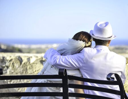 Summer wedding on Malta. Beautiful bride and groom on a cliff above the sea in a glamorous white wedding dress with scenic view to island, Malta. Happy woman, happy bride with scenic view in Malta.の写真素材
