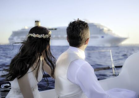 The groom and the bride look at cruise ship with the yachts on a sunny day. Daylight, outdoors.の写真素材