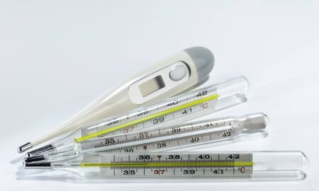 Digital and 3 mercury medical thermometers on neutral background. Indoor. Lamp lights. Closeup. Macro.の写真素材