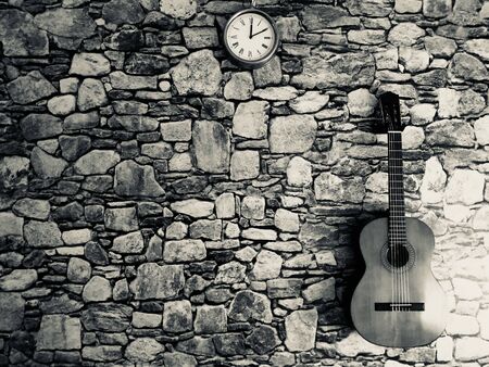 Guitar, clock, stone wallの写真素材