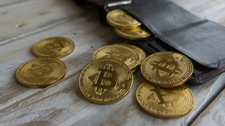 Golden Bitcoins with leather wallet on a wooden tableの写真素材